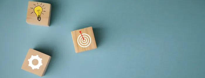 Drewniane klocki z ikonami: żarówka, cel z tarczą i zębatka